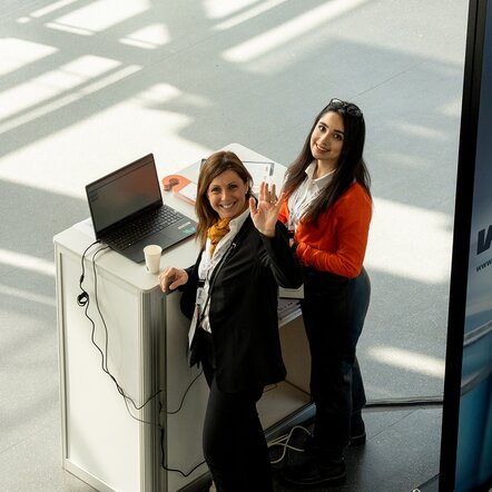 Zwei glückliche Frauen am Serviceschalter winken